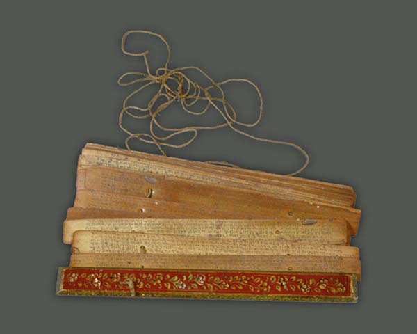 The string passes through holes made in the palm leaf pages of a pothi